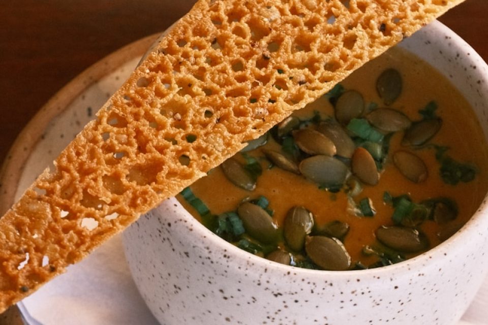 a bowl of soup with a piece of bread sticking out of it
