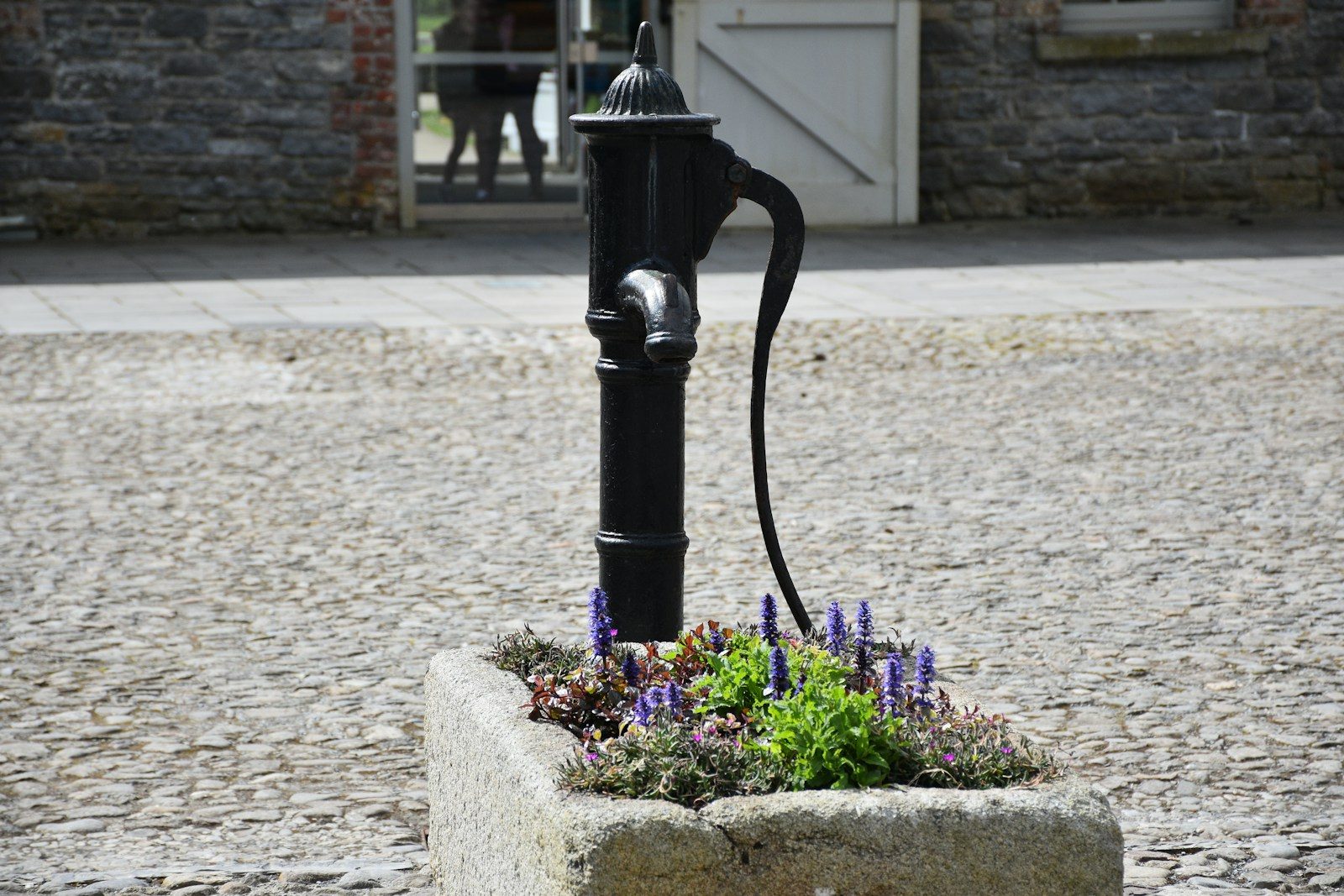 a black fire hydrant sitting on top of a cobblestone street
