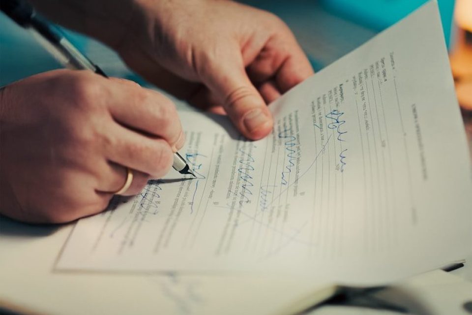 Man signing a document with a pen