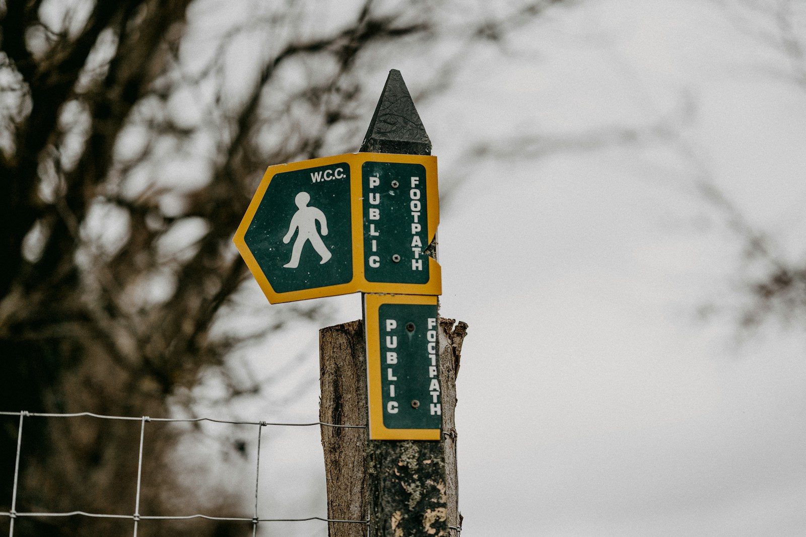 a street sign on a wooden post next to a fence