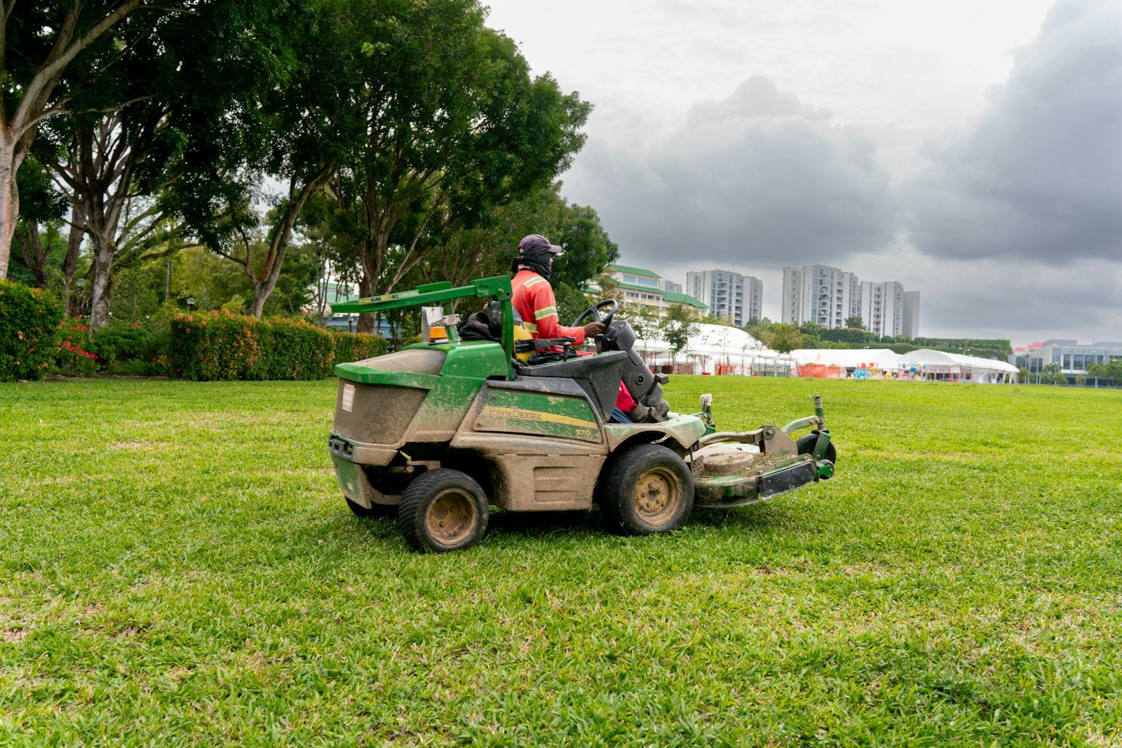 A man riding on the back of a green lawn mower