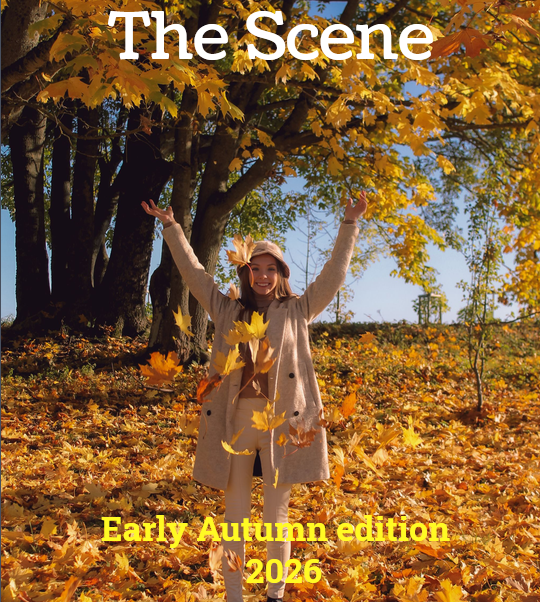 Woman standing with arms raised in front of woodland on ground deep in autumn leaves