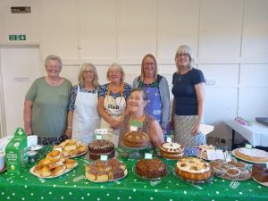 A group of ladies in front a of table with a selection of cakes